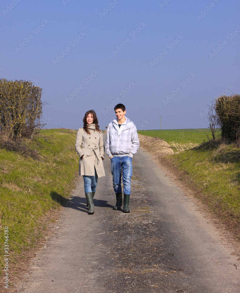 Couple of young people walking in the campaign in spring Couple of young people walking in the campaign in spring