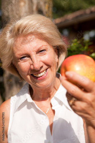 femme sénior qui montre une pomme