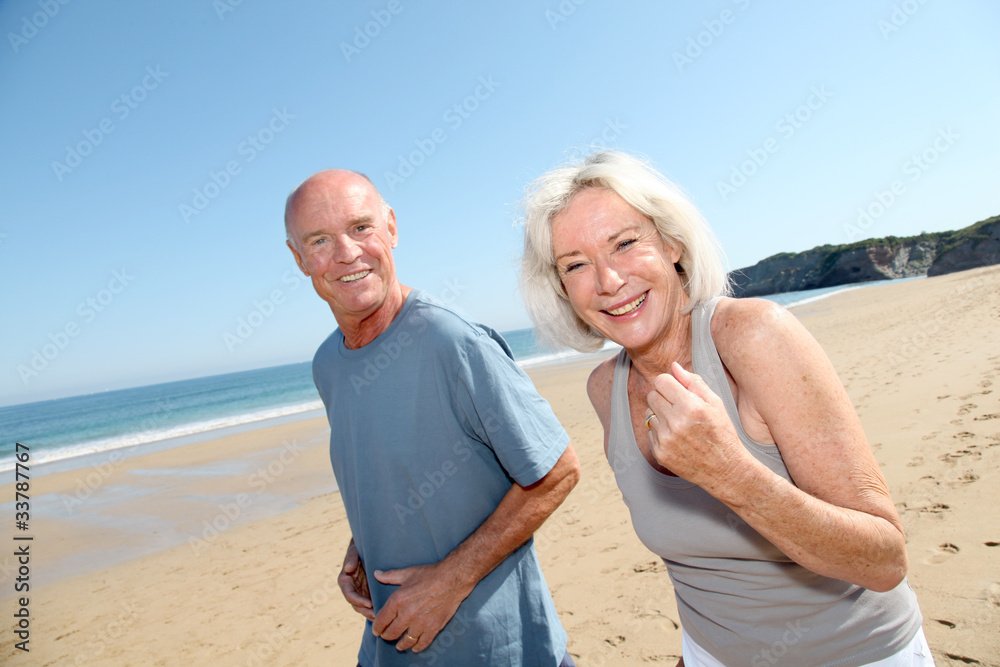 Senior couple jogging on a sandy beach