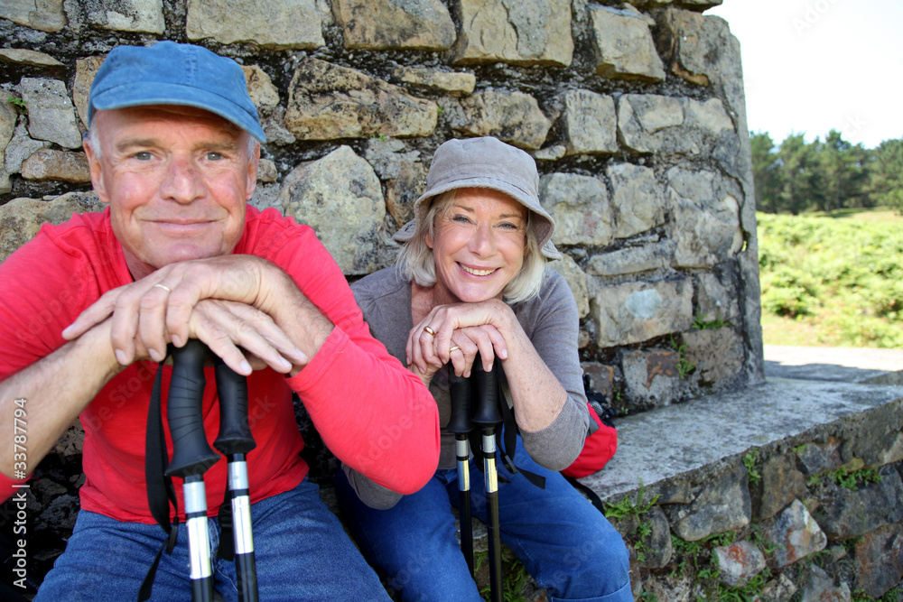 Portrait of happy senior hikers resting by stone house Portrait of happy senior hikers resting by stone house