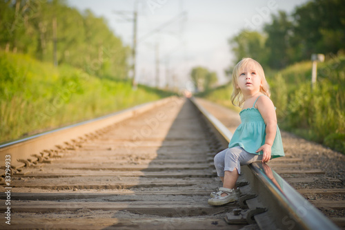 Adorable toddler girl sit on rail wait for train