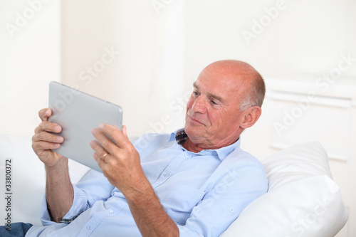 Senior man using electronic tablet at home