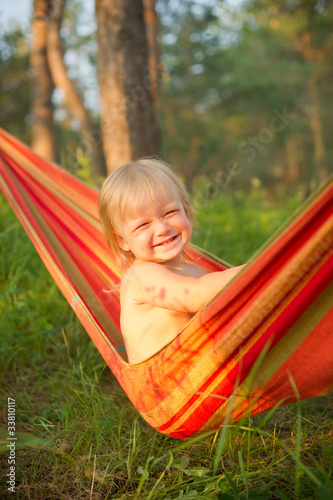 Adorable baby girl sit and smile relaxing in hammock