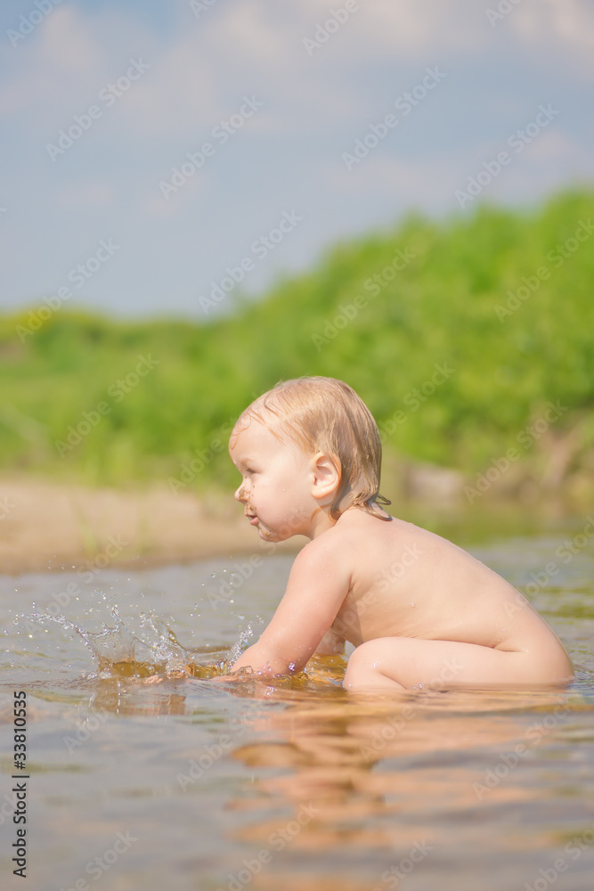 Adorable baby sit in river and play with sand and water Adorable baby sit in river and play with sand and water