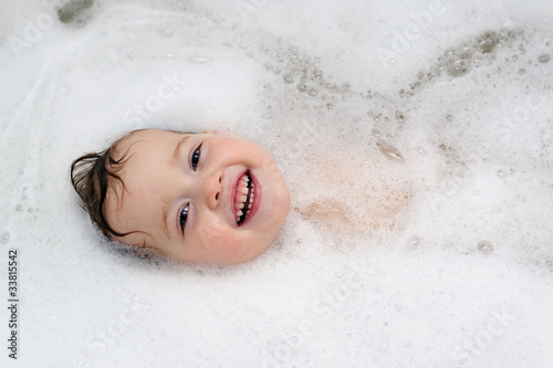 smiling baby is swimming in bath