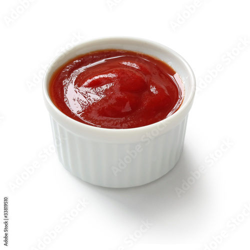 tomato ketchup in ramekin on white background