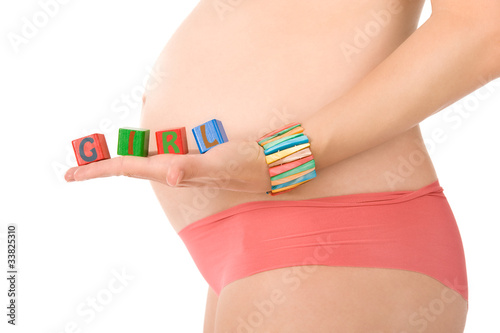Pregnant woman is holding blocks on her belly