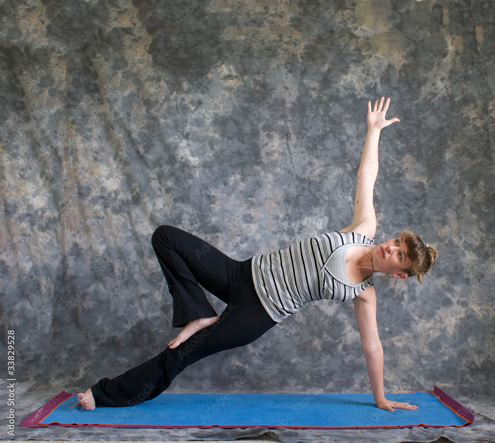 young woman doing Yoga posture Vasisthasana or side plank pose v