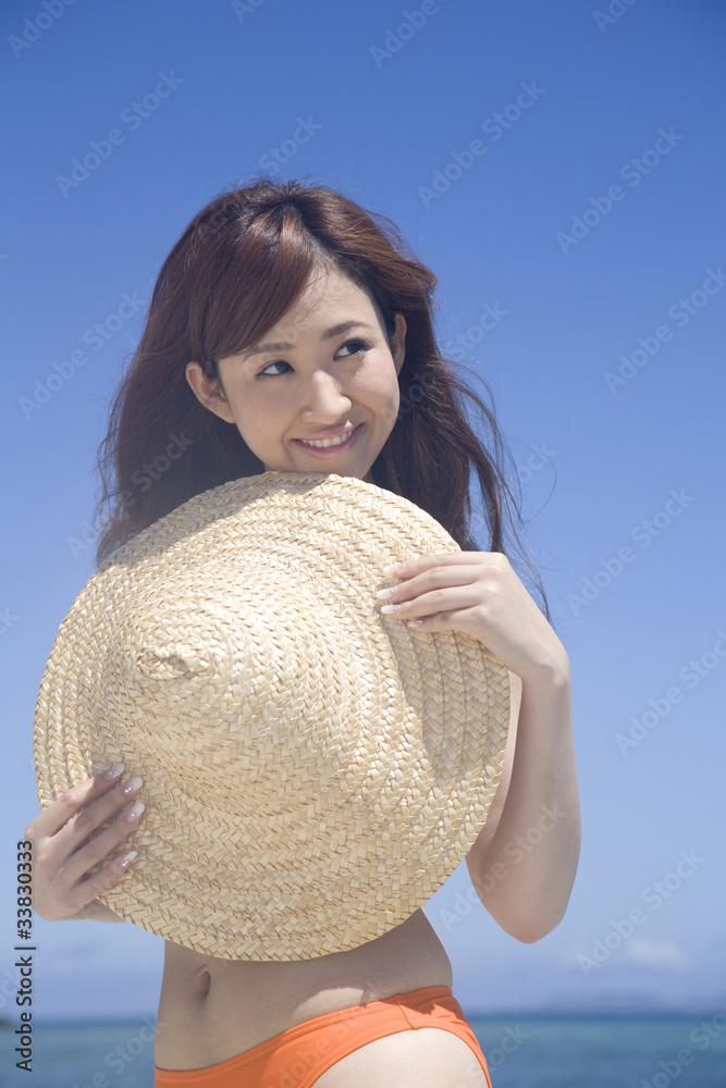 海辺で麦わら帽子を持つ水着女性 Stock Photo Adobe Stock