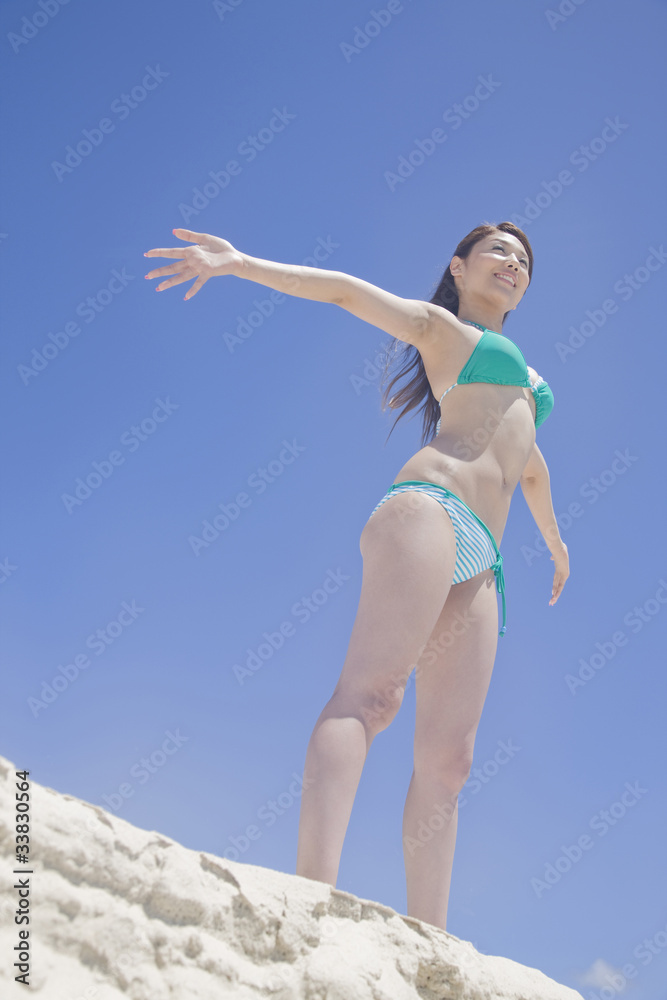砂浜で両手を広げる水着女性 砂浜で両手を広げる水着女性
