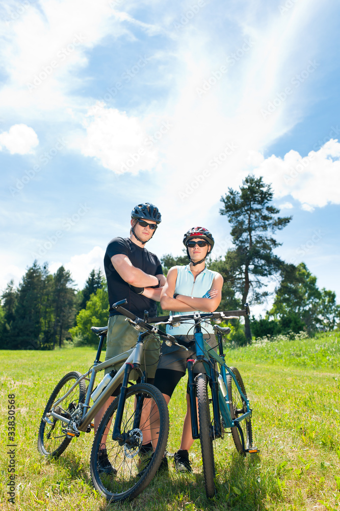 Sport mountain biking couple relax in meadows Sport mountain biking couple relax in meadows