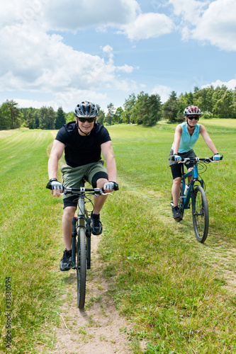 Sport couple riding mountain bicycles in coutryside