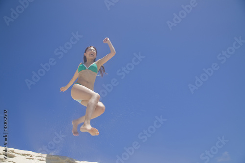 Fototapeta Naklejka Na Ścianę i Meble -  砂浜でジャンプする水着女性
