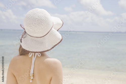 海を眺める帽子を被った女性の後ろ姿