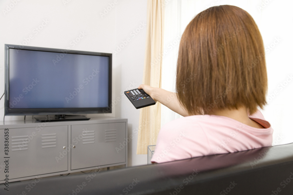 テレビをつける女性の後ろ姿 テレビをつける女性の後ろ姿