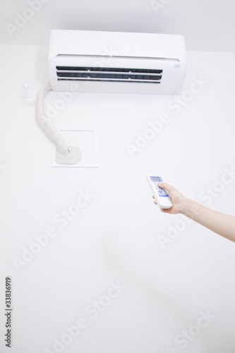 エアコンをつける女性の手元 © paylessimages