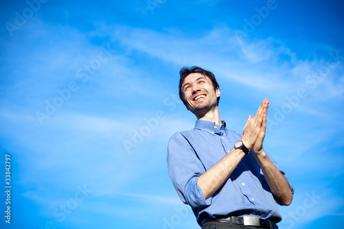 young business man in a blue shirt against the blue sky.