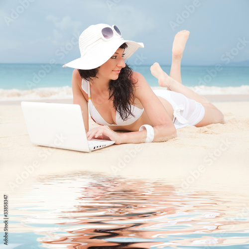 Cute woman with white laptop on the summer beach