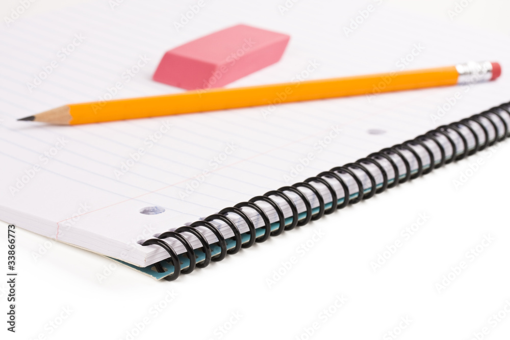 Pencil and eraser laying on notebook on white background