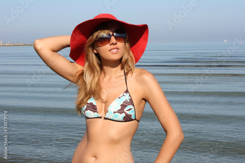 Happy young woman in swimsuit and red hat