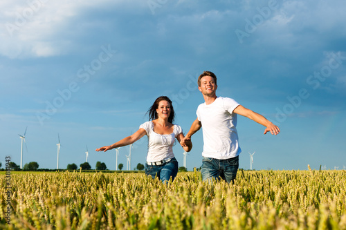 Happy couple running over grainfield