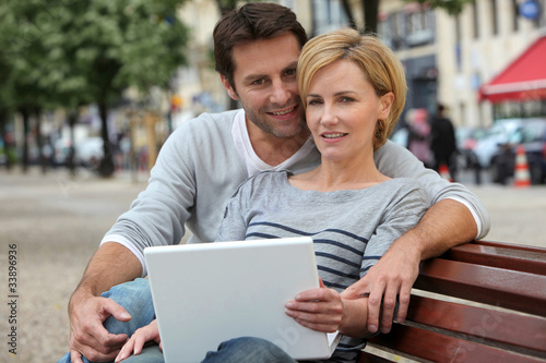 couple on a bench with laptop