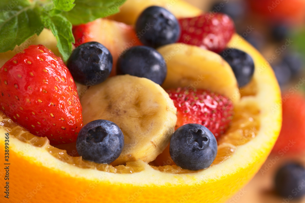 Fruit salad in half orange with banana slices and berries Fruit salad in half orange with banana slices and berries