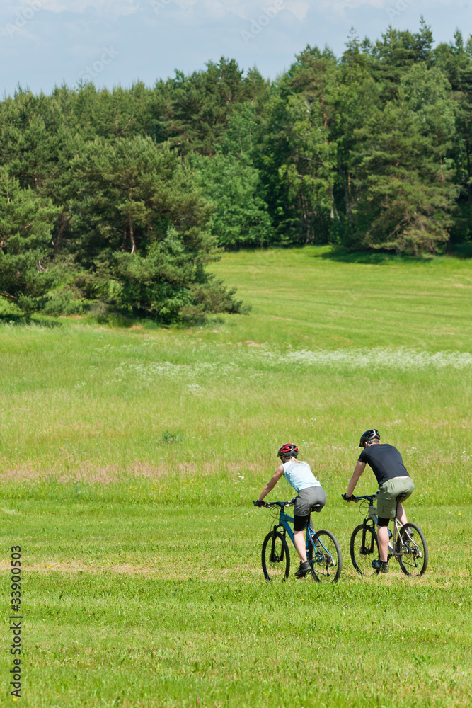Sport mountain couple biking downhill sunny meadows Sport mountain couple biking downhill sunny meadows