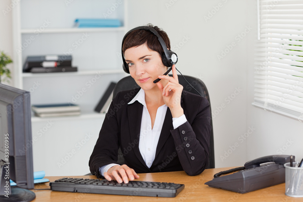Serious secretary calling with a headset Serious secretary calling with a headset