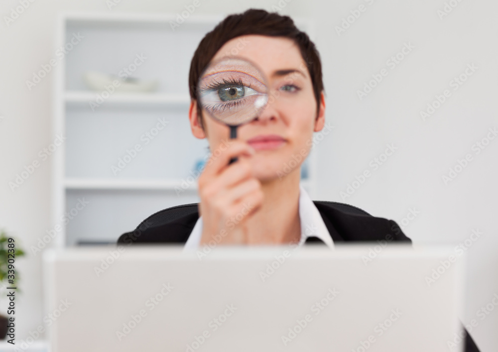 Office worker looking through a magnifying glass Office worker looking through a magnifying glass