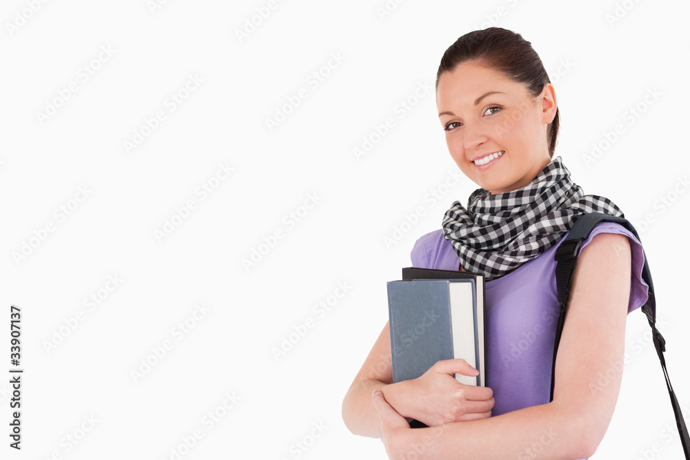 Good looking student holding books and her bag while standing Good looking student holding books and her bag while standing
