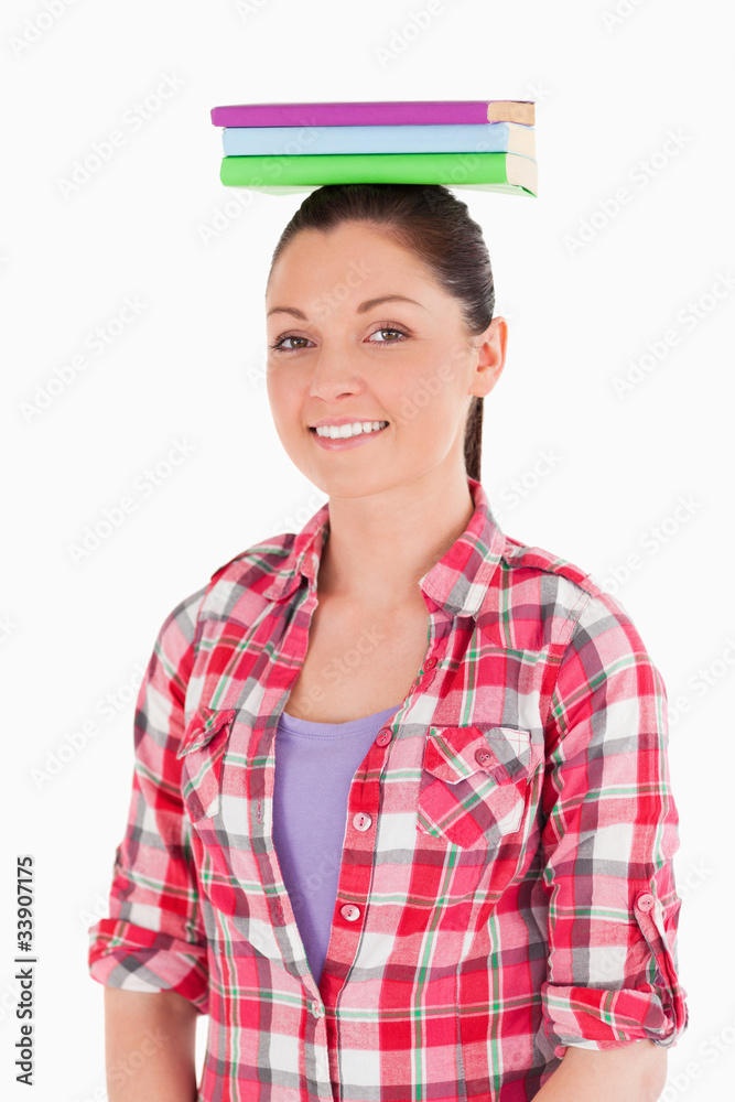 Good looking female holding books on her head while standing Good looking female holding books on her head while standing