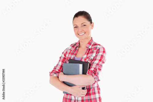 Good looking female posing with books while standing