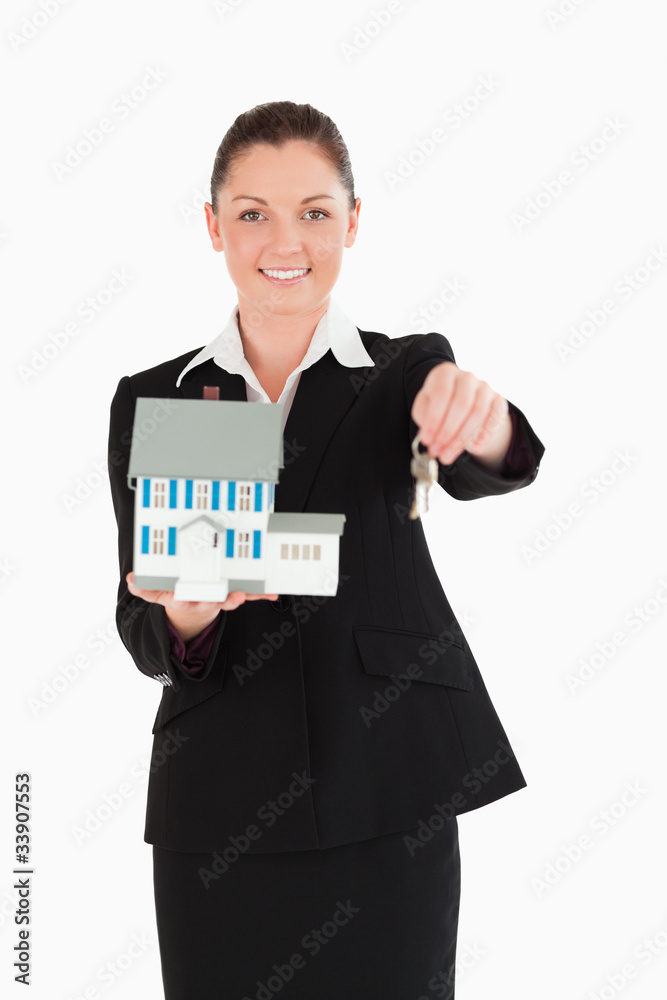 Attractive woman in suit holding keys and a miniature house Attractive woman in suit holding keys and a miniature house