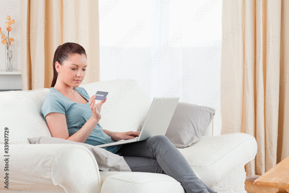 Lovely woman making an online payment with her credit card while Lovely woman making an online payment with her credit card while