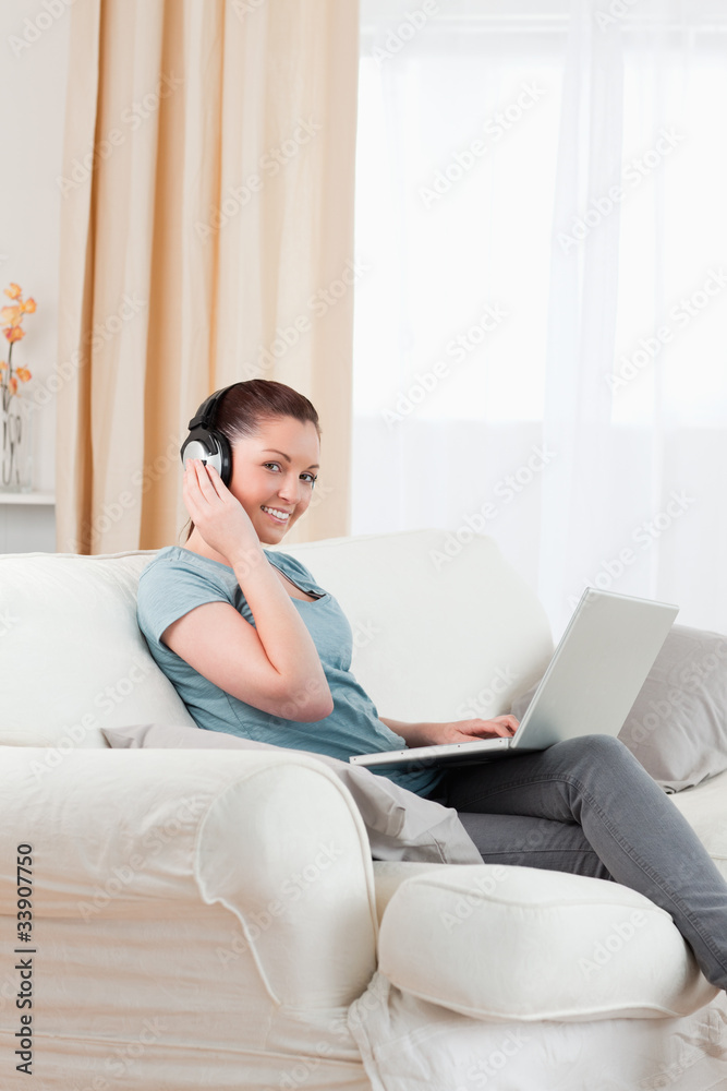 Good looking woman with headphones relaxing with her laptop whil Good looking woman with headphones relaxing with her laptop whil