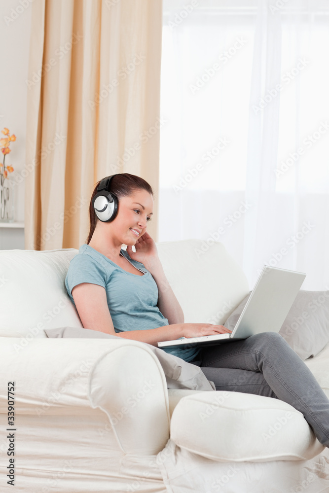 Beautiful woman with headphones relaxing with her laptop while s Beautiful woman with headphones relaxing with her laptop while s