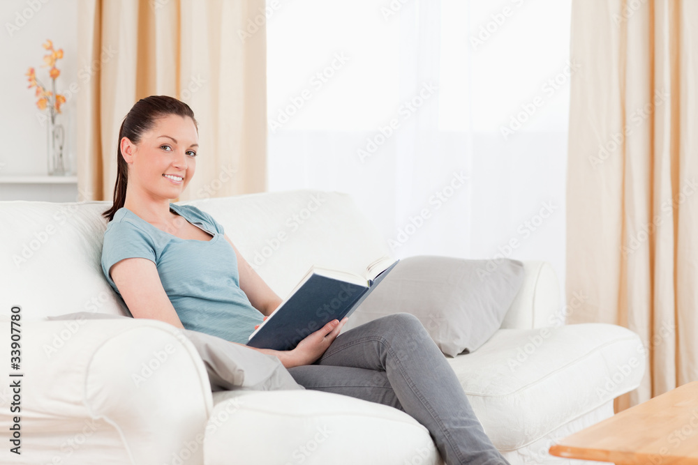 Beautiful woman reading a book while sitting on a sofa Beautiful woman reading a book while sitting on a sofa