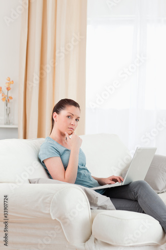 Sad woman relaxing with her laptop while sitting on a sofa