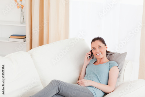 Lovely woman on the phone while lying on a sofa