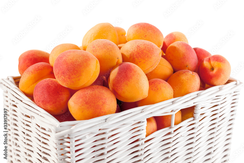 White wicker basket full of fresh apricots White wicker basket full of fresh apricots