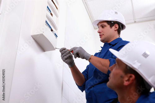 Electricians fitting a fuse box