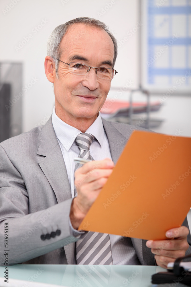 Older man making notes in a file Older man making notes in a file