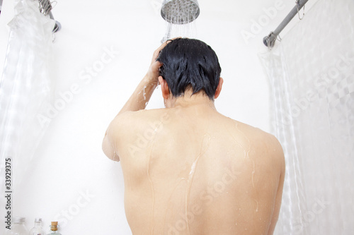シャワーを浴びる男性の後ろ姿