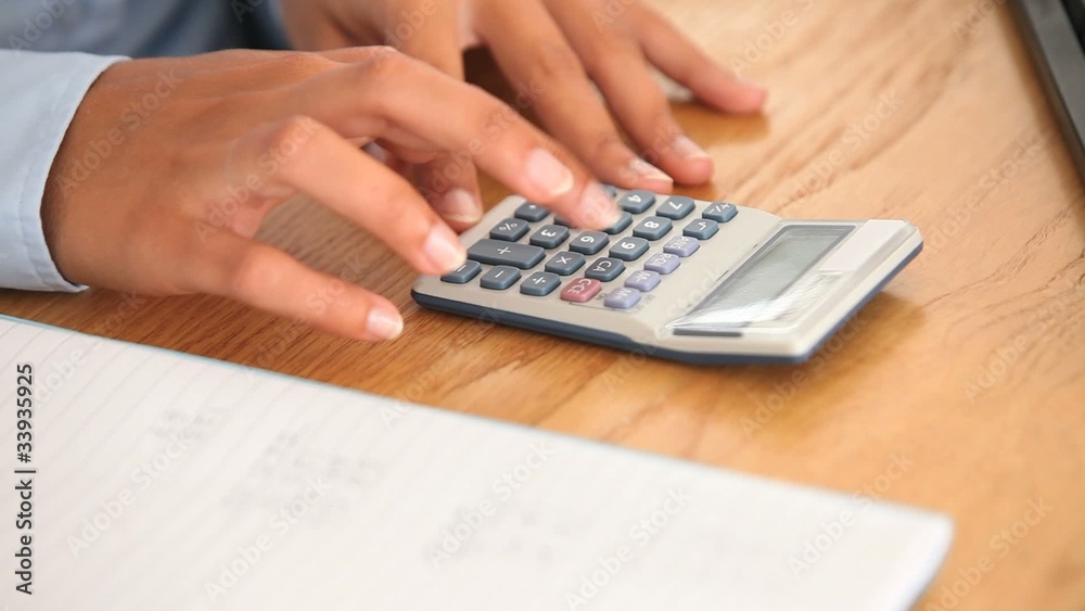 Hands typing on a calculator and writing Hands typing on a calculator and writing