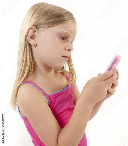 Little girl with pink smartphone on white background.