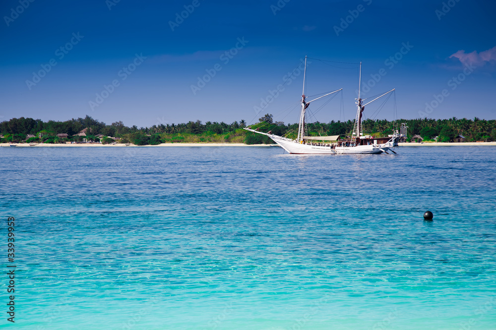Obraz premium Sailboat at a turquoise tropic island