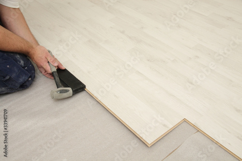 Canvastavla homme posant parquet flottant stratifié avec marteau