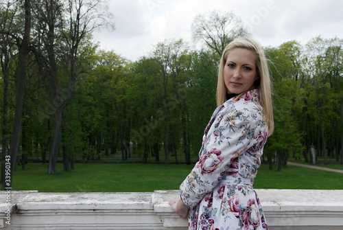 blonde girl standing against a background of park
