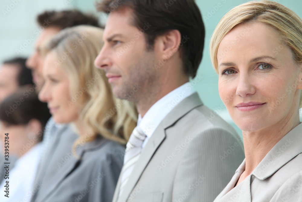Businesswoman standing in a line with colleagues Businesswoman standing in a line with colleagues